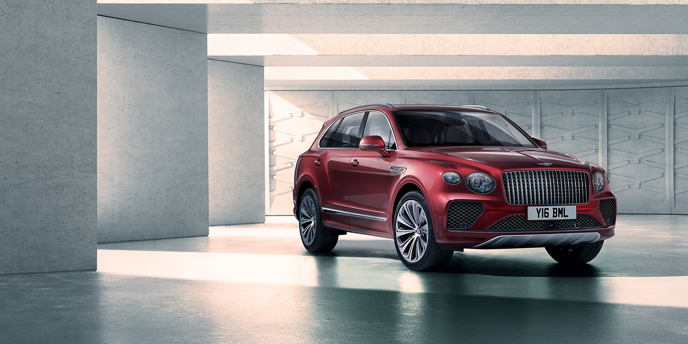 Bentley Muscat Bentley Bentayga Atelier Edition SUV in Rubino Red paint front three quarter against textured concrete wall