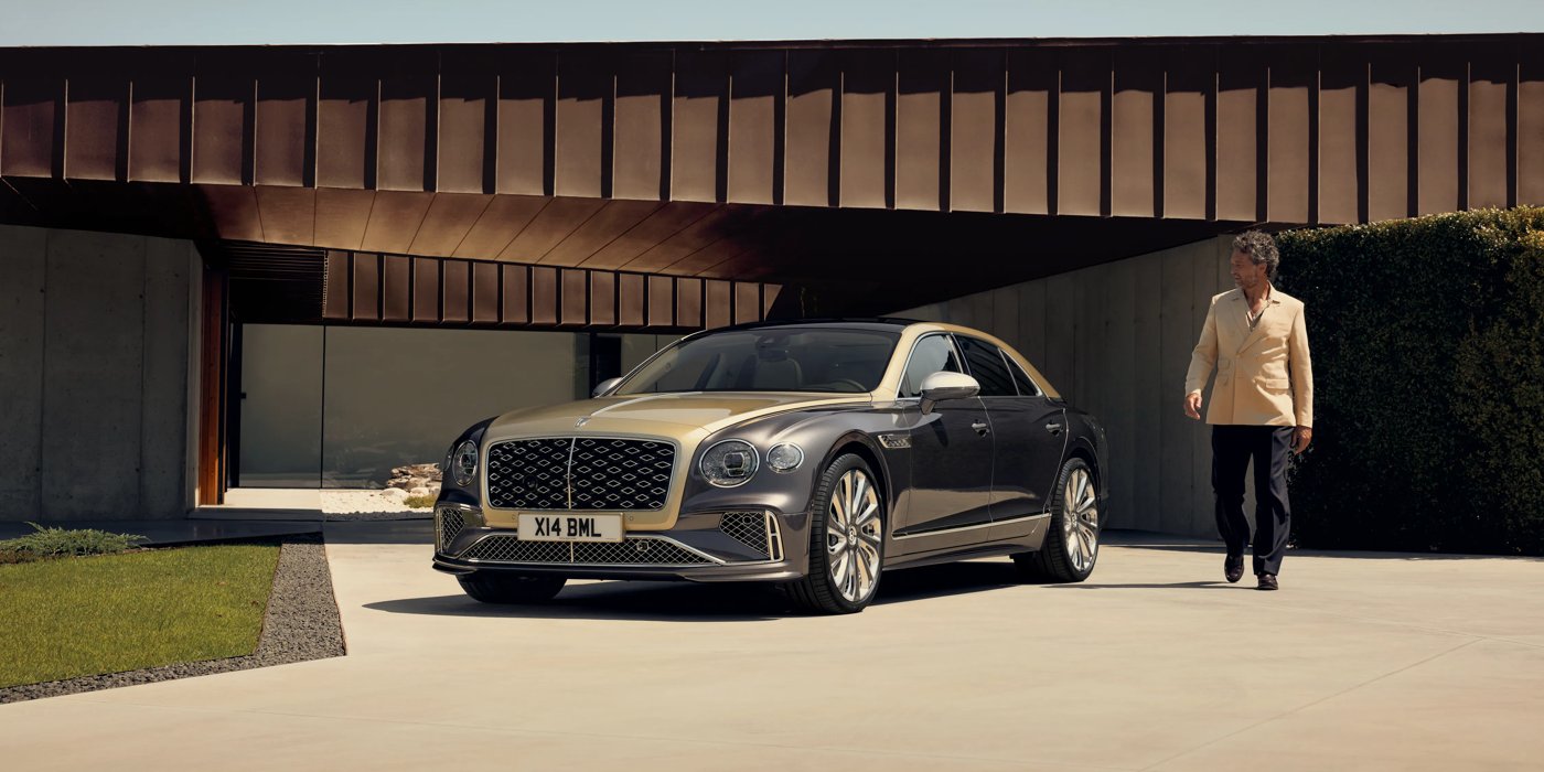 Bentley Muscat Bentley New Flying Spur Mulliner V8 hybrid sedan front three quarters in Rose Gold over Magnetic paint, parked near modern home