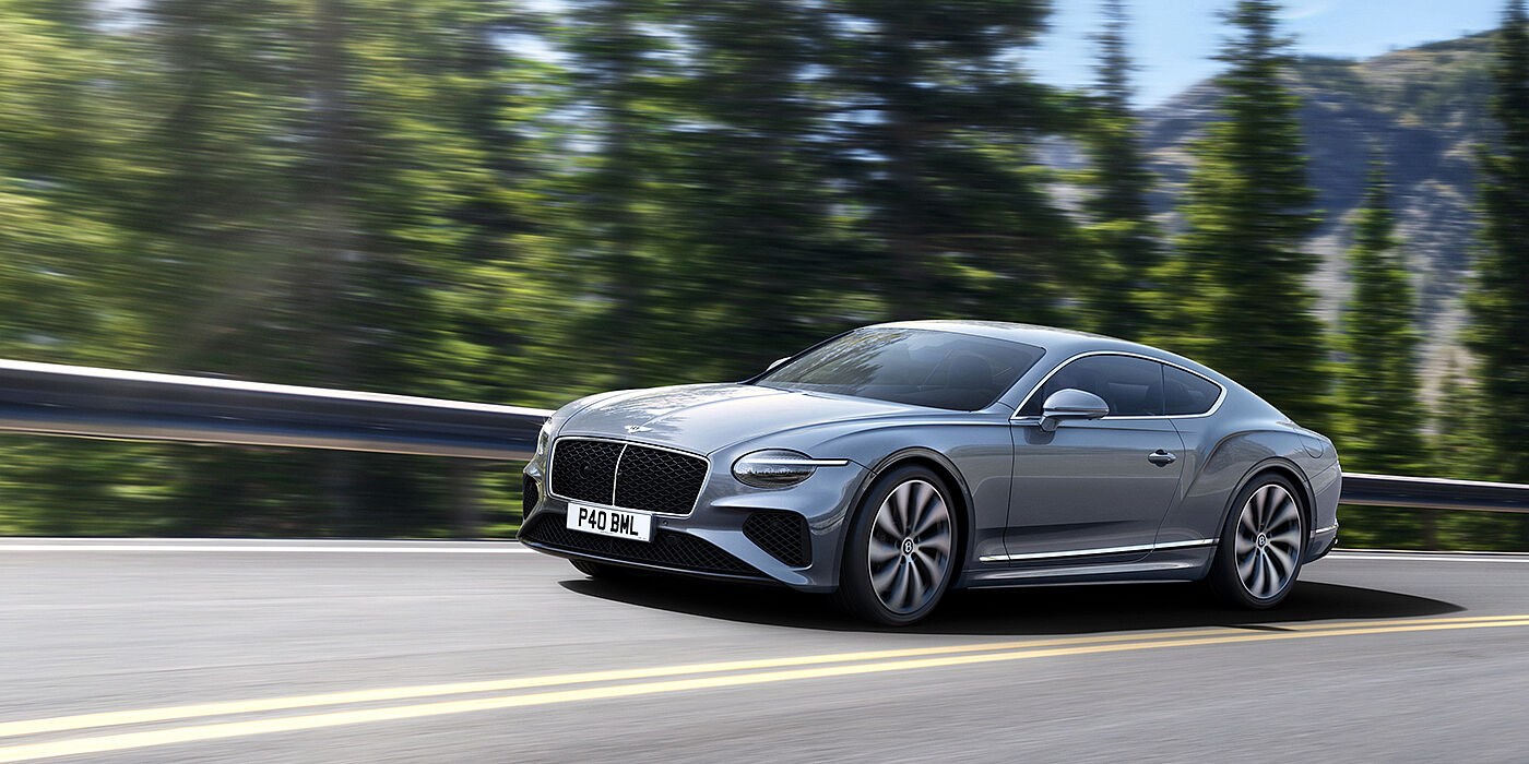 Bentley Muscat New Bentley Continental GT coupe in Silverlake paint and 22 inch ten-spoke wheels, driving dynamically on a tree-lined road in the sunshine