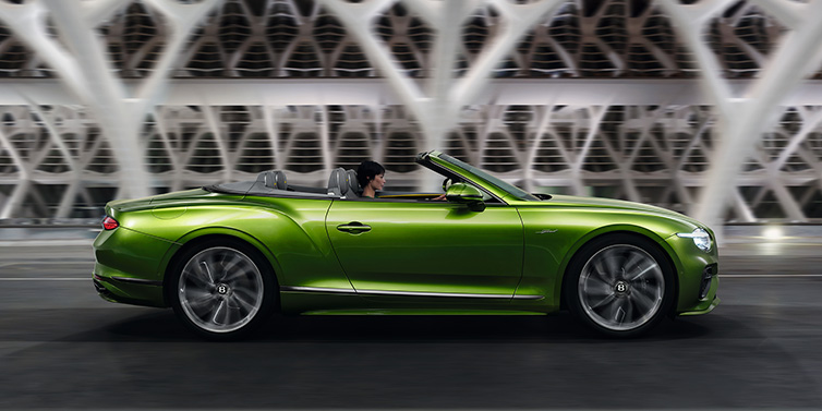 Bentley Muscat Bentley Continental GTC Speed convertible side profile in Tourmaline Green paint driving dynamically on a bridge at night