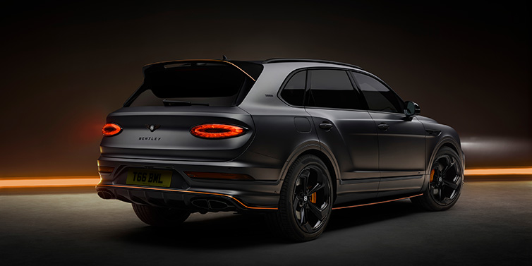 Bentley Muscat Bentley Bentayga S Black Edition SUV rear three quarter in Anthracite Satin paint against a dark red and yellow background