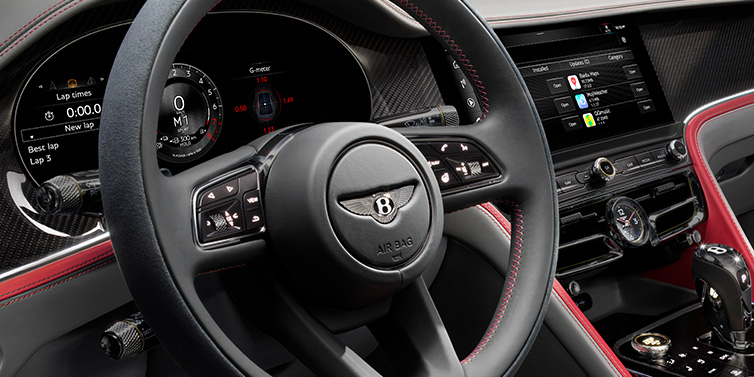 Bentley Muscat Bentley Flying Spur Speed sedan front interior detail showing steering wheel and driver screens surrounded with Hotspur red and Gravity Grey hides